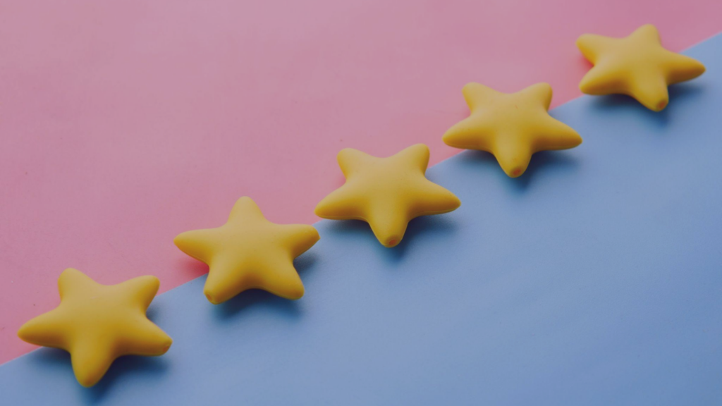 Avaliações positivas de produto ou serviço Imagem de uma linha de estrelas amarelas em fundo rosa e azul. As estrelas representam avaliações positivas, indicando que o produto ou serviço avaliado é de alta qualidade.