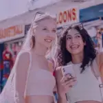 Cliente usando smartphone na frente de uma loja física. Descubra o Drive to Store e aumente suas vendas!